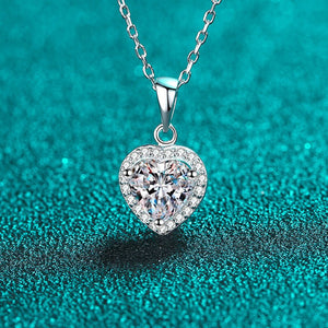 Heart-shaped diamond pendant on a chain against a teal background