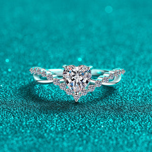Silver ring with a heart-shaped diamond on a teal glittery background