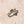 Silver ring with green gemstone on a beige stone surface