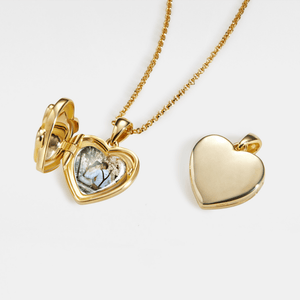 Gold heart locket necklace shown open and closed, featuring a smooth polished exterior and a photo insert inside, displayed on a delicate chain against a white background.