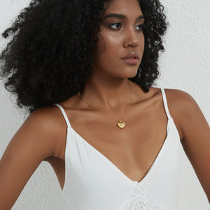 Gold heart locket necklace with a paw design, worn on a delicate chain on a model’s neck.