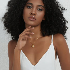 Gold heart locket necklace with a paw design, worn on a delicate chain on a model’s neck.
