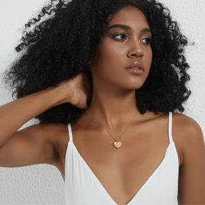 Gold heart locket necklace with a paw design, worn on a delicate chain on a model’s neck.