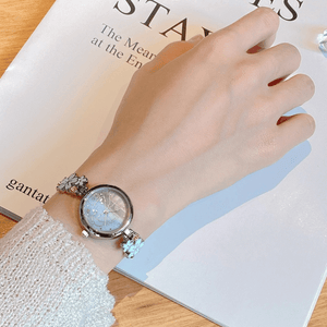 Hand wearing a decorative wristwatch on a magazine background