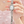 Silver Hello Kitty watch held by a hand with pink nail polish against a light background