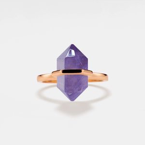 A gold-plated cocktail ring with a hexagon-shaped amethyst crystal set on a white background.