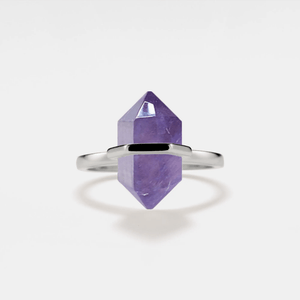 A gold-plated cocktail ring with a hexagon-shaped amethyst crystal set on a white background.