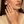 Close-up of a woman wearing a ring with a green gemstone on a neutral background