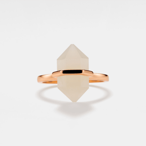 A hexagon-shaped moonstone crystal set in a gold-plated ring with a gold band.