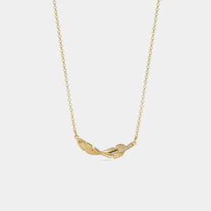 Gold feather necklace on a light gray background