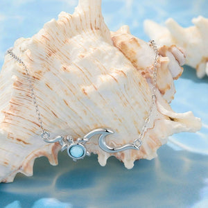 Silver sea turtle necklace with a blue gemstone on a large shell against a blue background