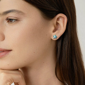 Close-up of a woman wearing turquoise starfish-shaped earrings.