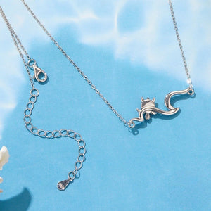 Silver sea turtle necklace with a wave shapped pendant on a blue background