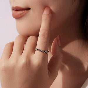 Close-up of a hand wearing a silver evil eye ring with blue stones, touching the face.
