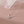 Butterfly-shaped necklace with colorful gemstones on a soft pink background
