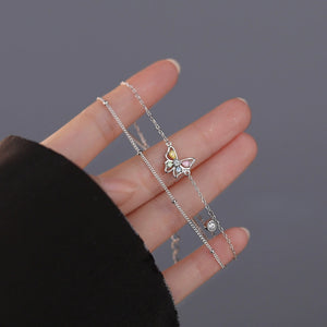 Silver bracelet with butterfly charms on a hand on a gray background