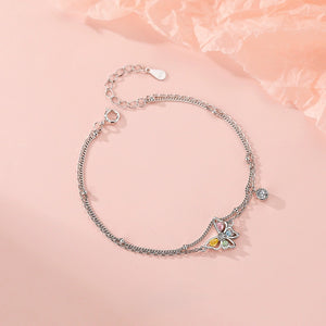 Silver bracelet with butterfly charms on a pink background