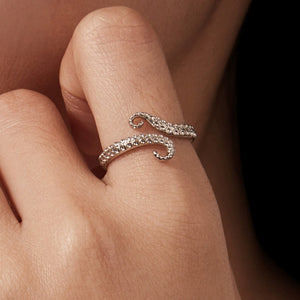 Silver ring with a octopus design on a person's finger against a blurred background