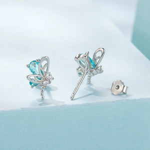 Butterfly-shaped earrings with blue gemstones on a light blue background