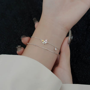 Silver bracelet with butterfly charms on a wrist on a black background