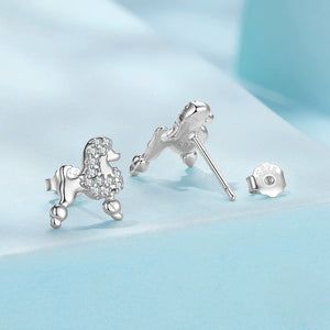 Silver poodle-shaped earrings on a light blue background