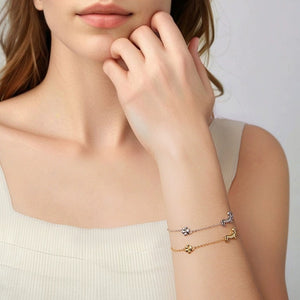 Model wearing gold and silver chain bracelets featuring a dachshund dog charm and a small paw print accent