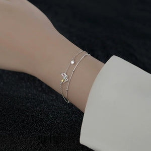 Silver bracelet with butterfly charms on a wrist on a black background