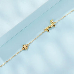 Gold bracelet with a dachshund dog design on a light blue background