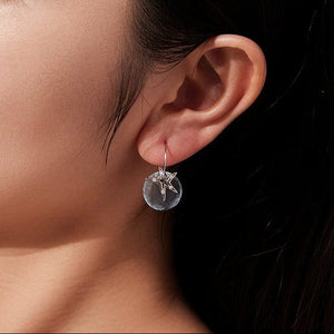 Close-up of an ear wearing a blue shell earring with a starfish design.