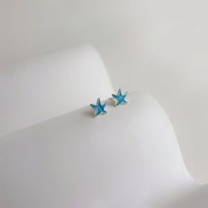Blue starfish-shaped earrings on a white background