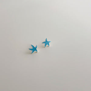 Pair of blue starfish-shaped earrings on a light gray background