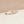 Gold and silver ring with heart and infinity symbol on a beige surface