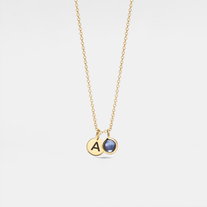 A gold-plated sterling silver necklace with a small circular charm featuring a letter 'A' and a crystal glass projection bead inset.