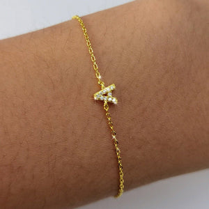 Gold bracelet with a letter 'A' charm on a wrist against a white background
