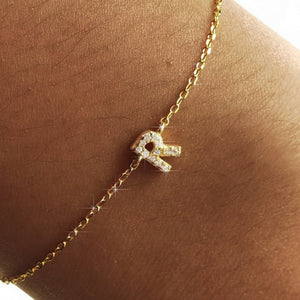 Gold necklace with a letter 'R' pendant on a person's neck