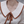 Close-up of a person wearing a beige sweater with a brown collar and a gold necklace with interlocking rings.