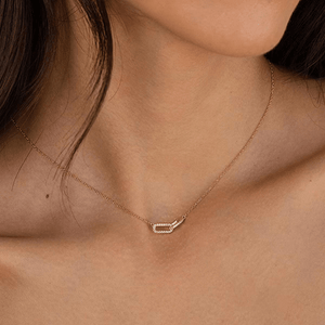Close-up of a gold necklace with a diamond pendant on a person's neck.