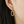 Gold hoop earring worn by a person with dark hair.