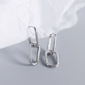 Silver chain-style earrings on a light gray background