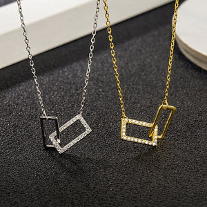 Two necklaces, one gold and one silver, with geometric pendants on a dark textured surface.
