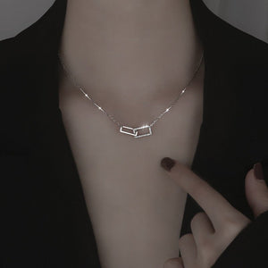 Two interlocking rectangle pendant necklaces, one plated in silver and the other in gold, set against a dark background.