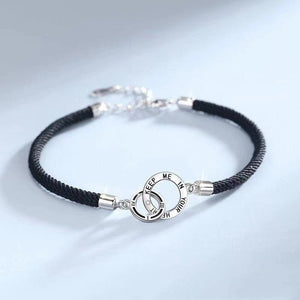 A matching set of interlocking ring bracelets, one with a black cord and another with a silver chain, laid on a white surface.