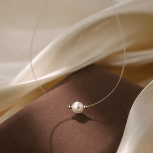 Pearl necklace on a brown surface with a soft beige fabric background