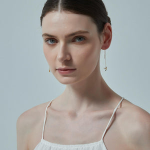 Woman wearing gold earrings against a plain background