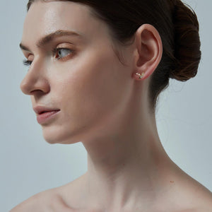 Close-up of a woman wearing a gold earring against a neutral background