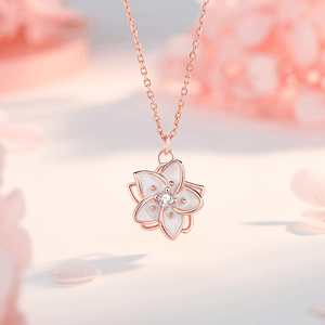 Rose gold necklace with a floral pendant on a soft pink background