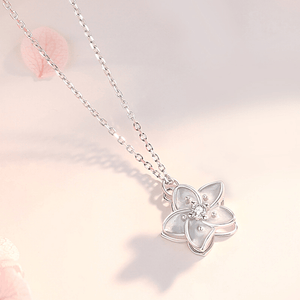 Silver necklace with a butterfly pendant on a soft pink background