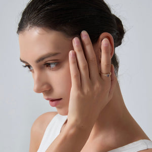 Woman wearing a diamond ring on her finger against a plain background