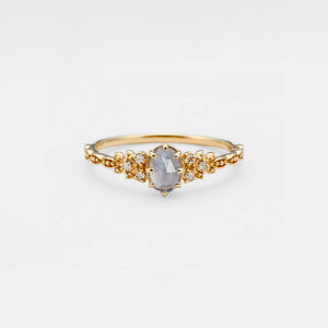 Gold ring with a central gemstone on a light gray background