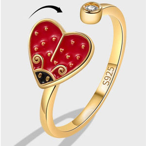 Gold ring with a red heart-shaped design on a white background